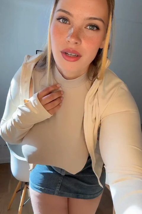 Curvy girl in a denim mini skirt and tight braless top dancing and bouncing in her living room.