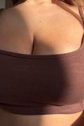 Busty blonde model bottomless in the sunlight, revealing her big natural boobs from a sports bra in a high-quality NSFW X-reel.