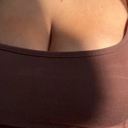 Busty blonde model bottomless in the sunlight, revealing her big natural boobs from a sports bra in a high-quality NSFW X-reel.
