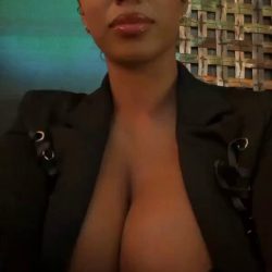 Stunning social media model in a nightclub, wearing a blazer to showcase huge boobs and deep cleavage in a high-quality NSFW viral photo.