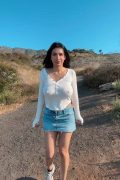 Hot amateur girl posing on a scenic mountain peak, capturing an exciting outdoor wardrobe flash from her white braless top in an NSFW clip.