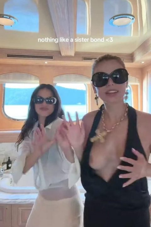 Famous American model and television personality wearing an ultra-revealing plunging black dress and oversized dark sunglasses while dancing outdoors on a luxury yacht-pic 3