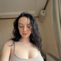 Busty brunette exposes big natural boobs from tight braless top in bedroom